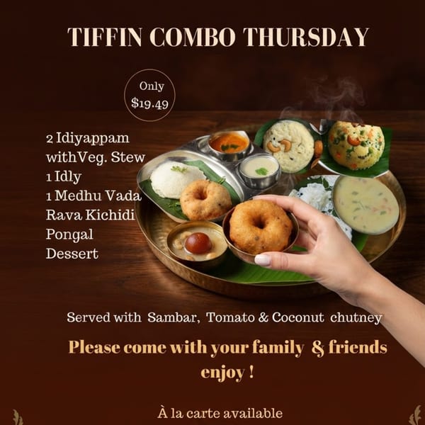 A hand holds a Medhu Vada from a Tiffin Combo platter with various South Indian dishes.